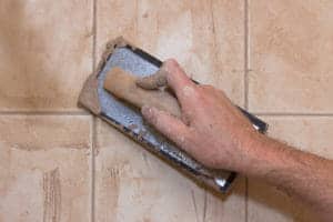 hand applying grout to tile with rubber float
