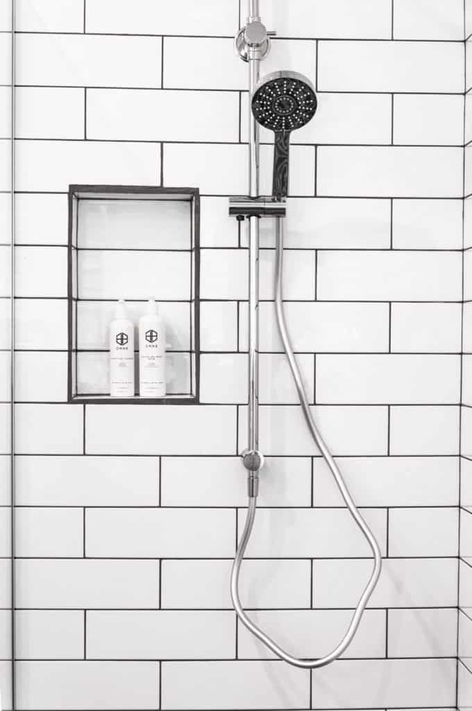 Adjustable shower head with hose on sliding bar in tile shower